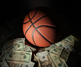 Basketball on black background lying next to pile of cash