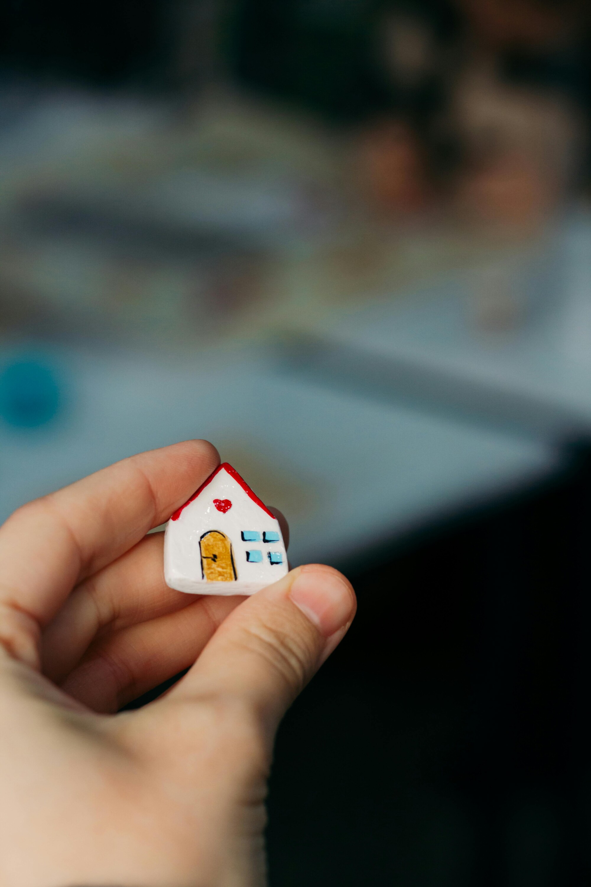 A hand holds a ceramic house.
