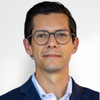 Stephen Hayes is a white man in his mid-40s with glasses. He is wearing a dark blue suit and white shirt.